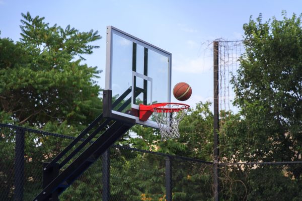 Basketball shield, basket and ball on background of sky, trees, street in summer.